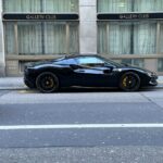 Marke: Ferrari Modell: Ferrari 296 GTB Farbe: Schwarz Baujahr: Nicht erkennbar (wahrscheinlich modernes Modell) Besondere Merkmale: Sportfelgen, gelbe Bremssättel, mittig angebrachter Lufteinlass, typisches Ferrari-Emblem auf dem Kotflügel, aerodynamisches Design Es handelt sich um einen Ferrari 296 GTB in der Farbe Schwarz mit Sportfelgen und gelben Bremssätteln. Das genaue Baujahr ist nicht erkennbar, aber es handelt sich wahrscheinlich um ein modernes Modell.